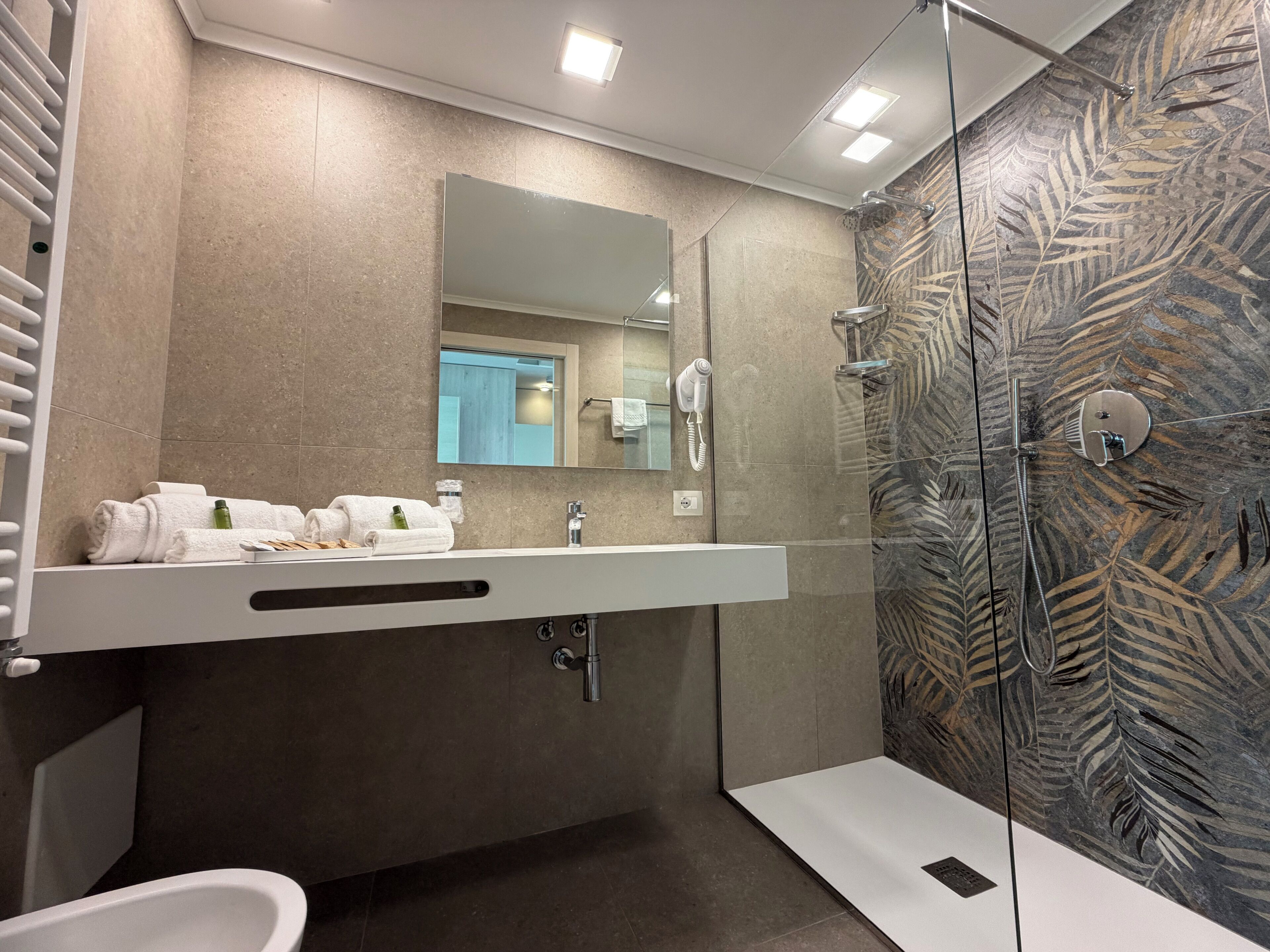 A modern bathroom with a glass shower, a large mirror, and a white vanity.