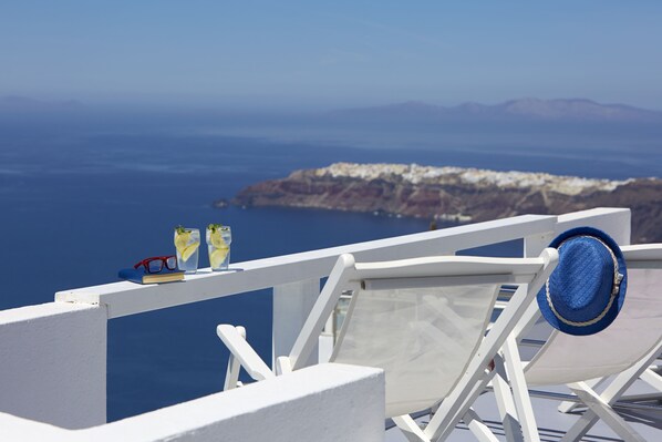 Un balcón blanco con vista al mar y una isla distante.
