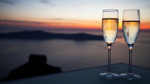Two champagne flutes on a table with a sunset view.