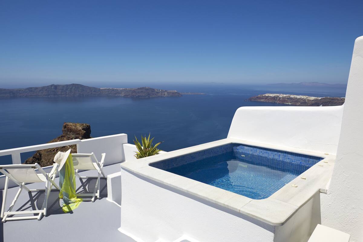 A white infinity pool with a clear view of the sea and distant islands.