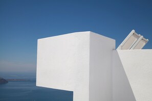Un edificio blanco con vista despejada al océano y una isla distante.