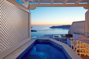 Zona de piscina con vista al mar y una pérgola blanca.