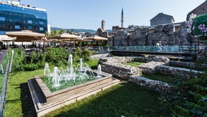 Une cour avec une fontaine, des espaces de repos en plein air et des structures en pierre d’époque.