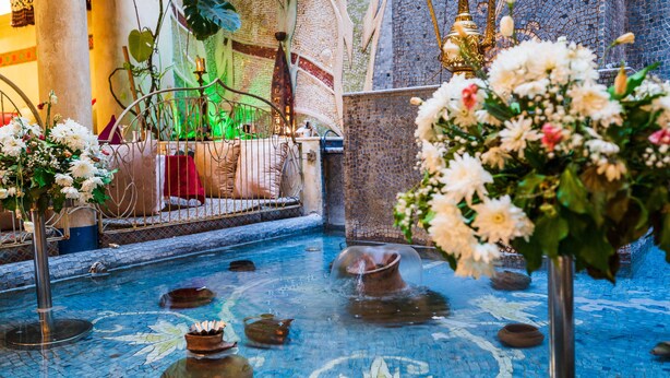 Un espace piscine agrémenté de mosaïques, de vases décoratifs et de fleurs.