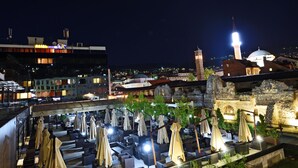 Une terrasse sur le toit, dotée d’un espace extérieur aménagé et offrant une vue sur un bâtiment historique surmonté d’un minaret.