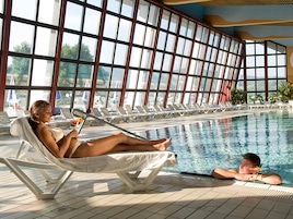 Un área junto a la piscina con sillones de descanso y una alberca.