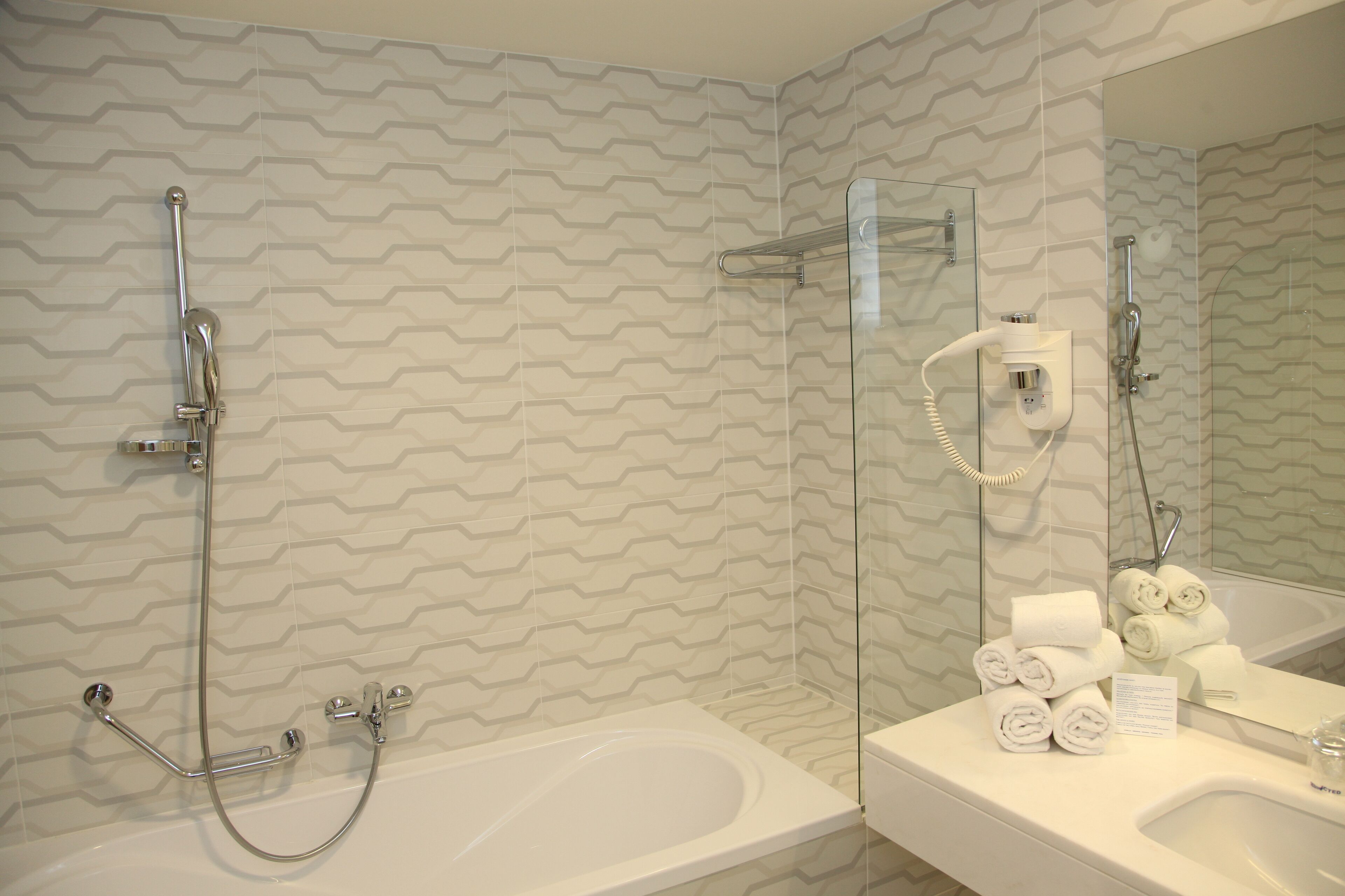 Un baño con ducha, bañera y lavamanos con toallas.