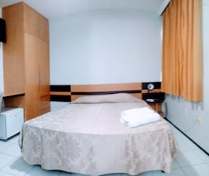 A bedroom with a bed, a wardrobe, a nightstand, and a wall socket. - Seamar Hotel (Fortaleza)