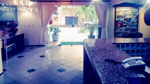 A hotel lobby with a tiled floor, a reception desk, a telephone, and a wall with a collage of photos. - Seamar Hotel (Fortaleza)
