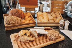 Diverse broden en gebak op houten planken in een bakkerij.
