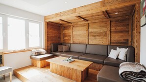 Ein modernes Wohnzimmer mit einer Wand in Holzoptik, einer Couch, einem Couchtisch und einer Bank.
