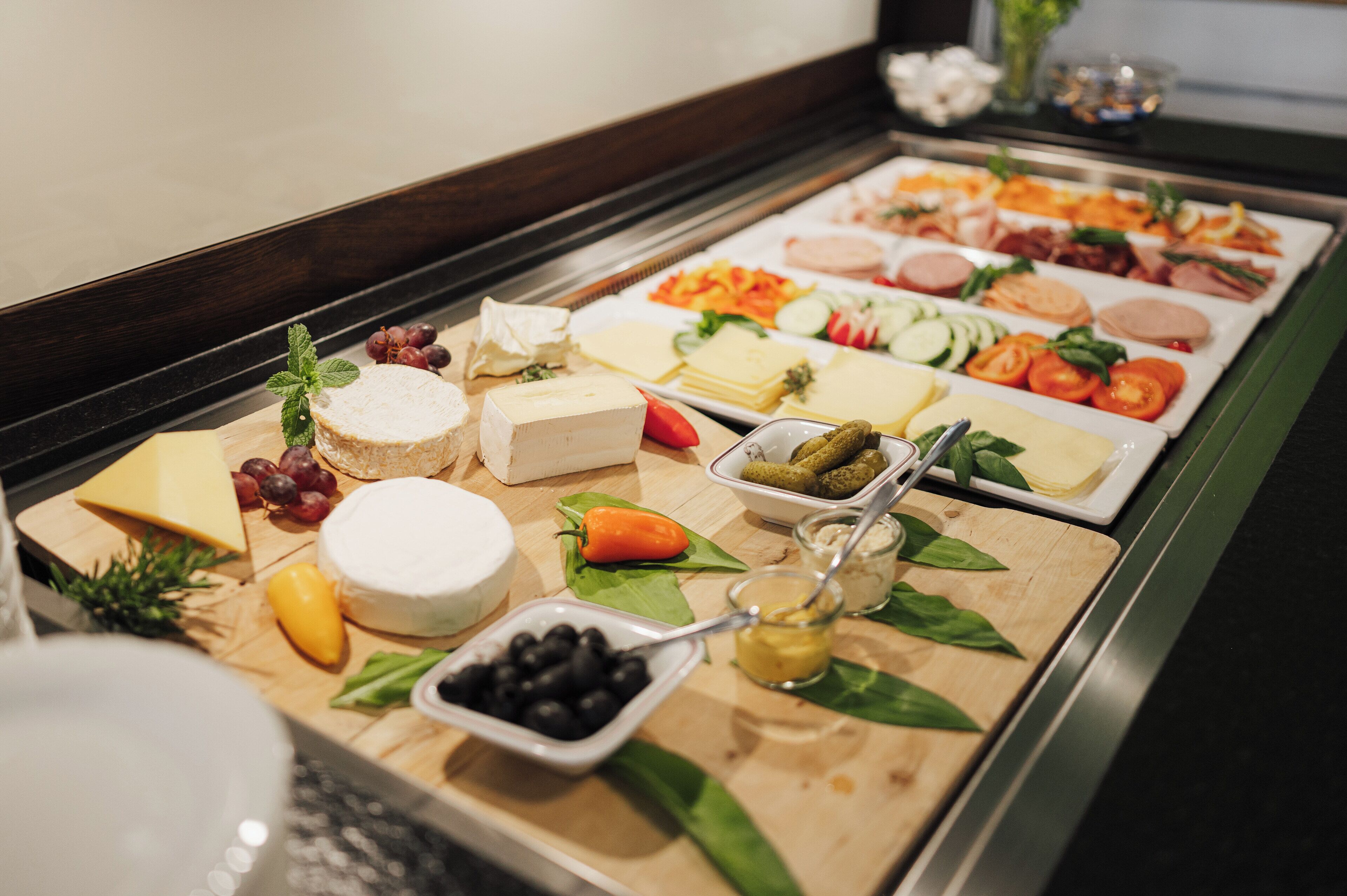 A buffet with various cheeses, fruits, and vegetables.