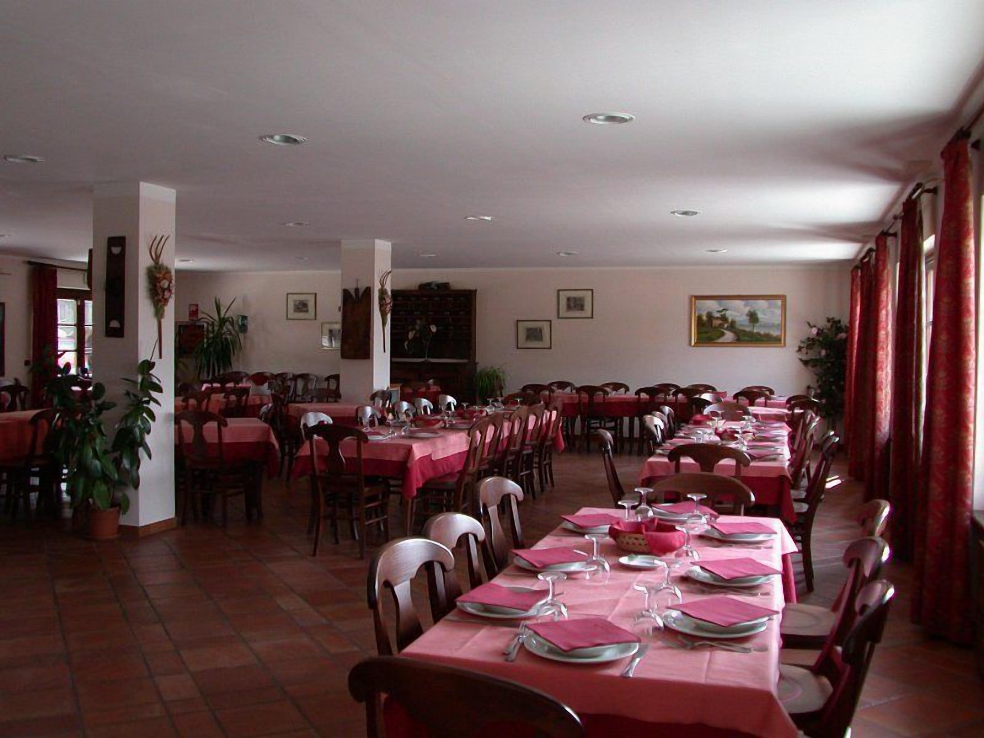 A dining area with multiple tables set for meals, chairs, and potted plants.