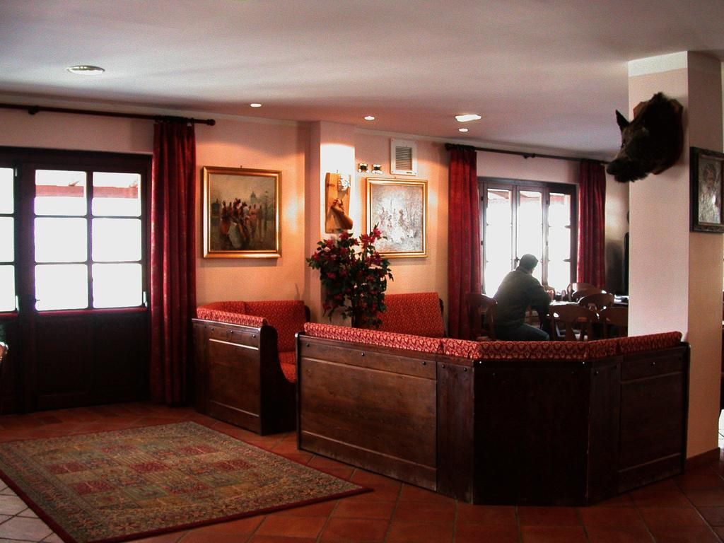 A room with a wooden bench, a rug, a painting, and a mounted animal head.