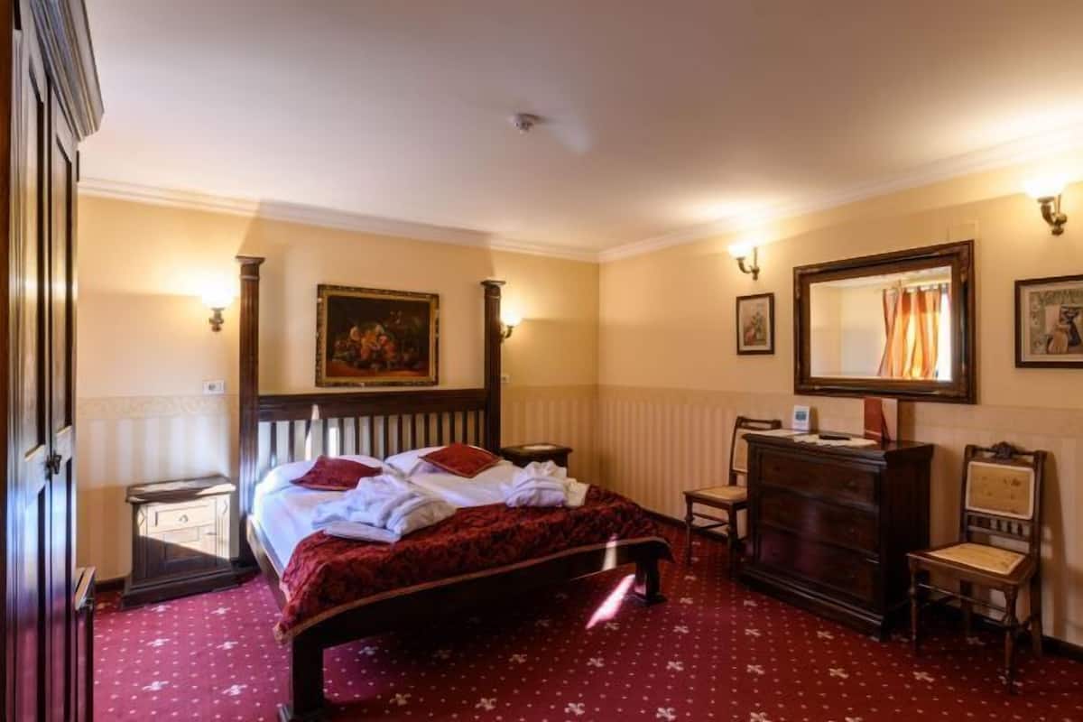 Habitación de hotel con cama, cómoda, silla, escritorio y espejo.