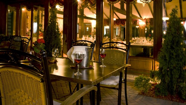 An outdoor dining area with wicker chairs and tables, a metal pitcher, and wine glasses. - Boutique hotel Casa del Sole (Timisoara)
