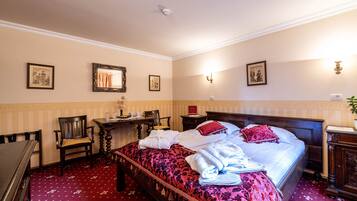 Ein Hotelzimmer mit einem großen Bett, einem Schreibtisch, einem Sessel und einem kleinen Tisch.