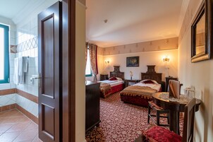 Una habitación de hotel con dos camas, un escritorio, una silla, un aparador y un ventanal con cortinas.