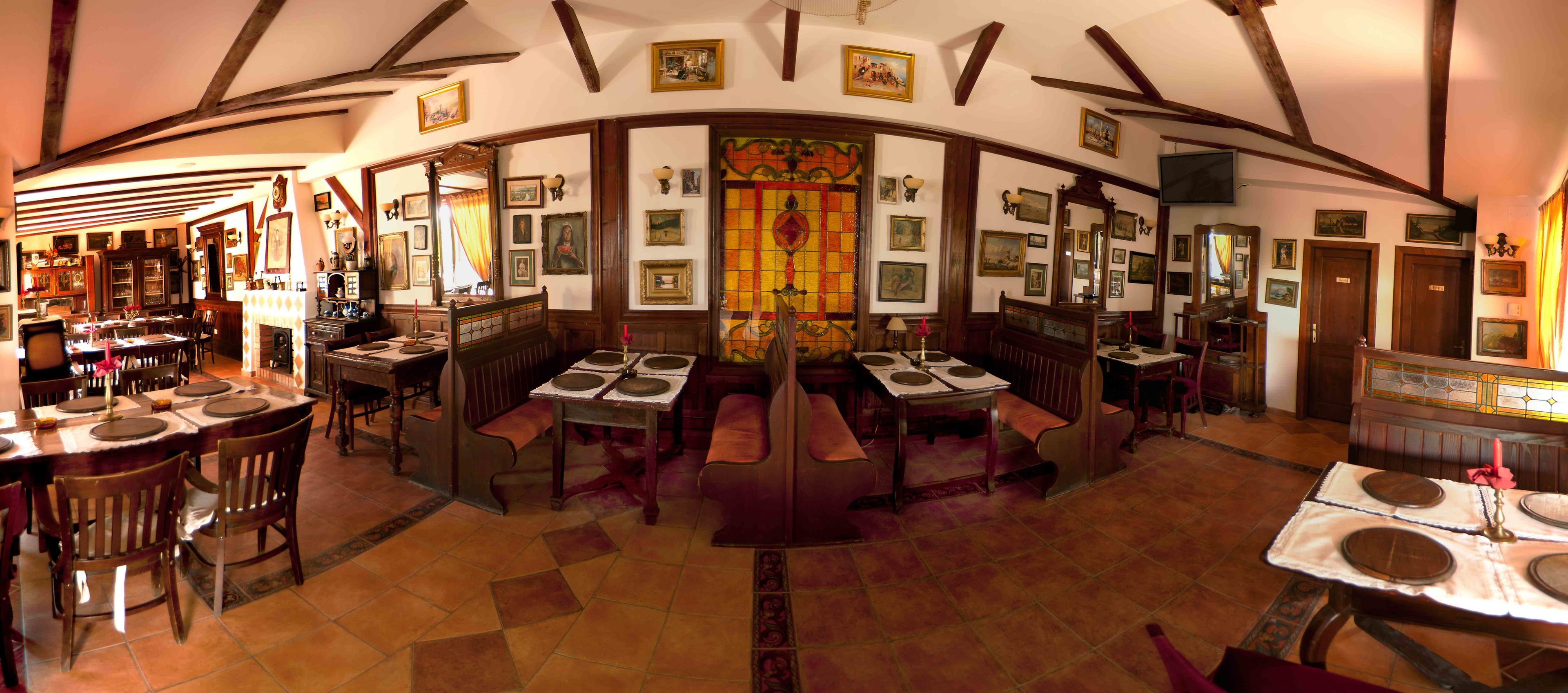 Un restaurant doté de poutres en bois apparentes, de nombreuses tables et chaises, et d’un vitrail central.