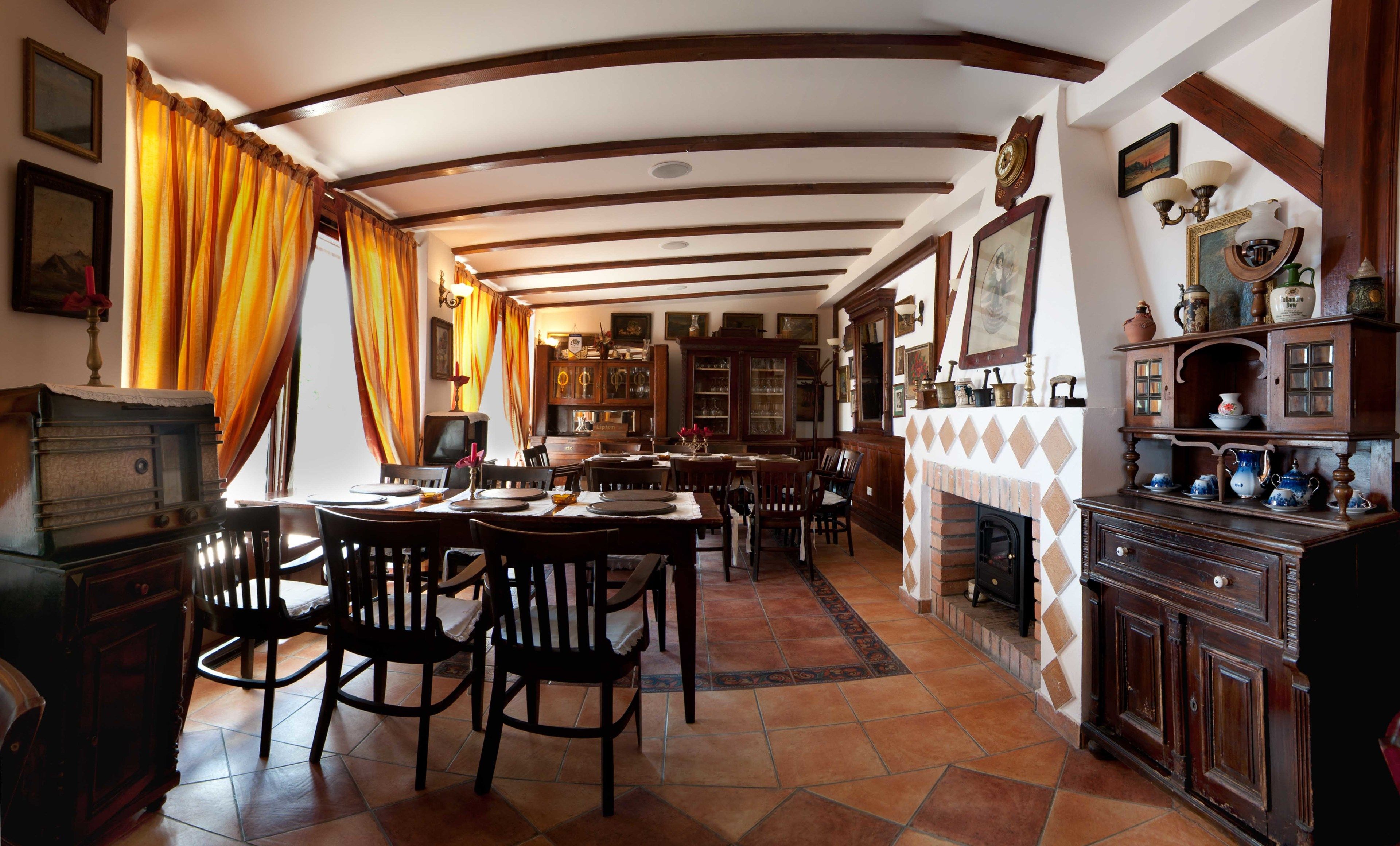 Comedor tradicional con techo alto, vigas de madera y chimenea.