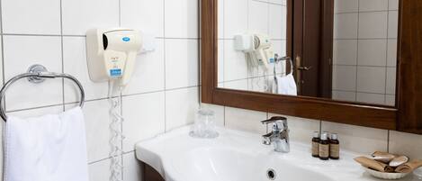 A bathroom with a white sink, a towel rack, a hairdryer, and a mirror.