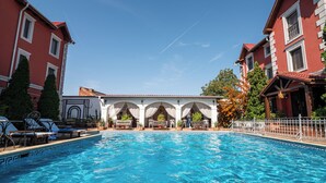 A swimming pool with lounge chairs and a covered seating area, surrounded by buildings with red facades and white trim. - Boutique hotel Casa del Sole (Timisoara)
