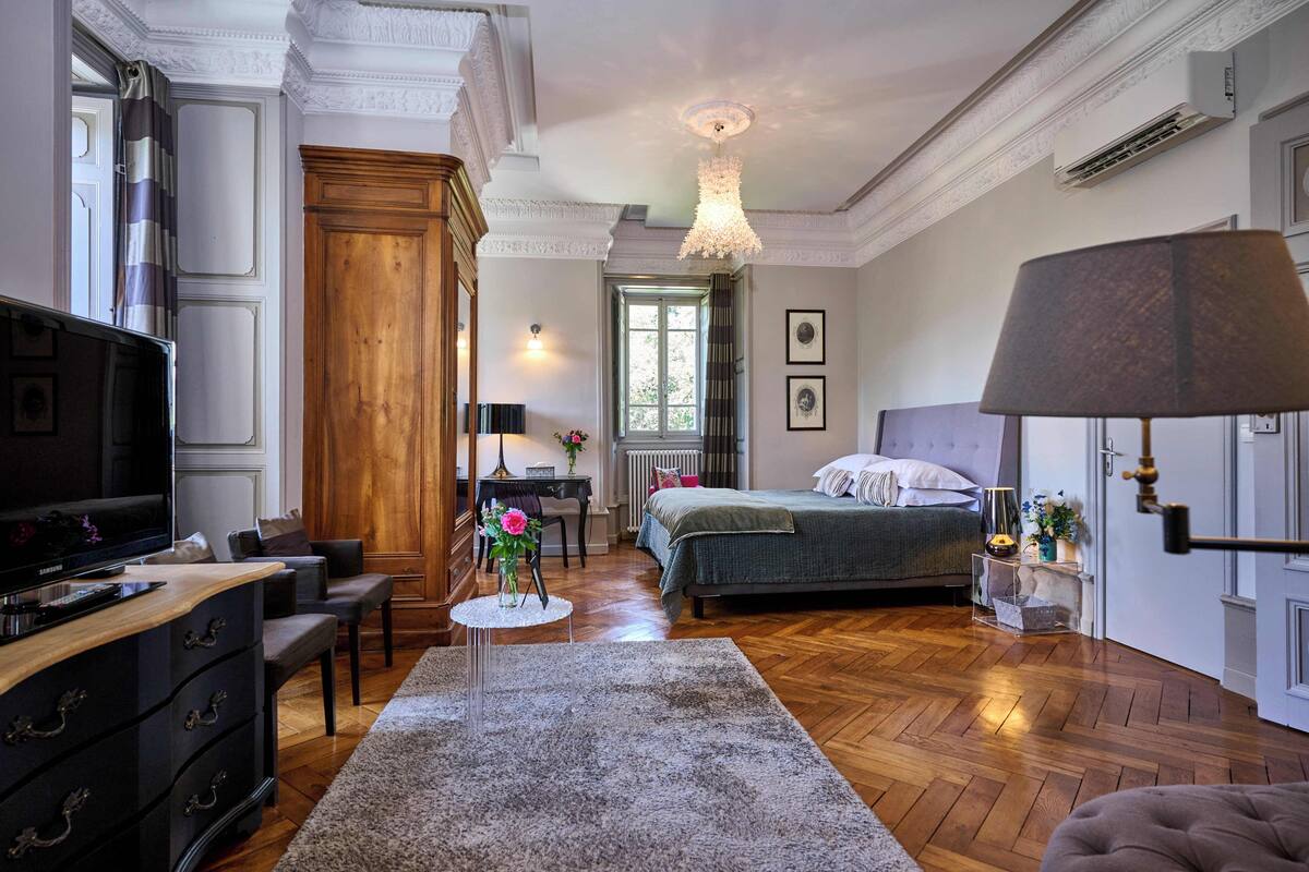 A bedroom with a bed, a TV, a desk, and a chair.