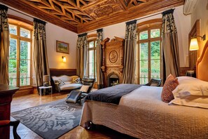 Um quarto com cama, lareira, sofá e poltrona.