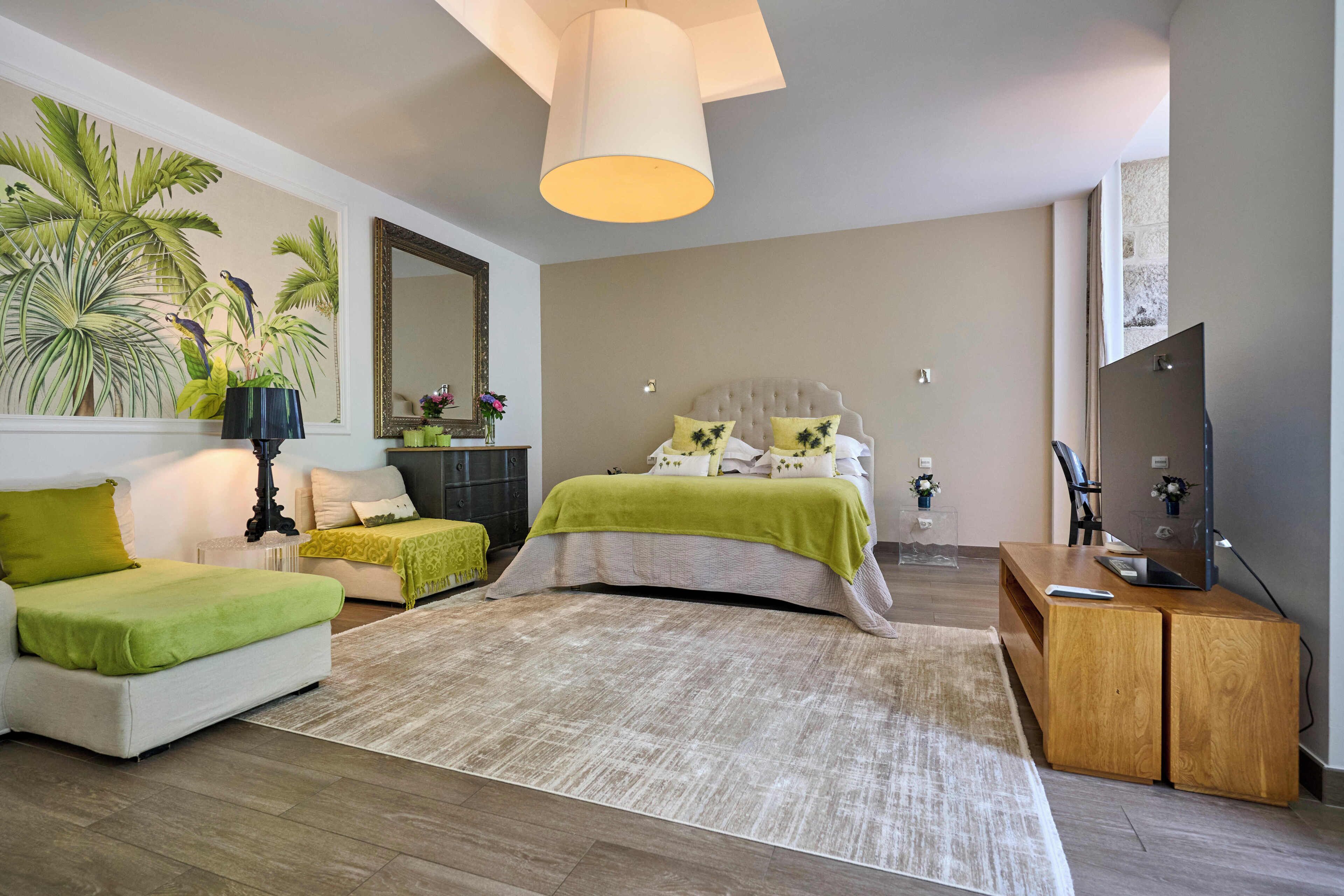 Un dormitorio moderno con cama, sofá, escritorio, televisor y un espejo grande.