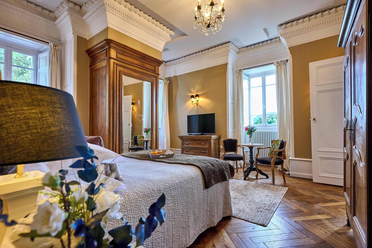 A well-appointed bedroom with a large bed, a television, a desk, and a chair.