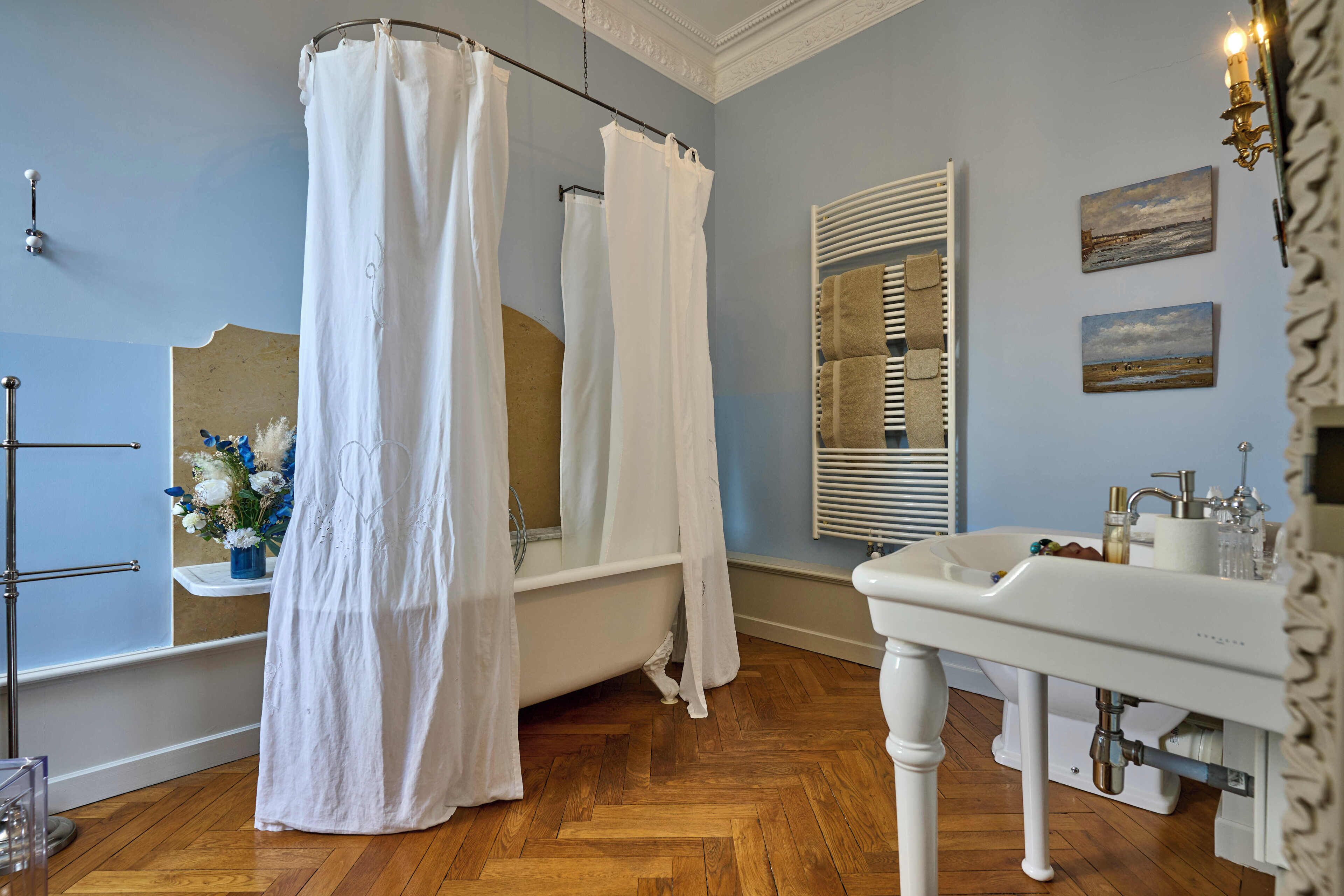 Une salle de bain avec une baignoire, un lavabo, un miroir et un rideau de douche.