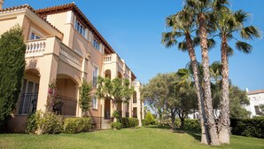 A two-story building with a beige facade, multiple balconies, and palm trees in the foreground. - Grupotel Club Turquesa Mar (Ciutadella de Menorca)