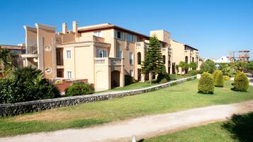 A multi-story hotel with a stone facade, balconies, and a well-maintained lawn.