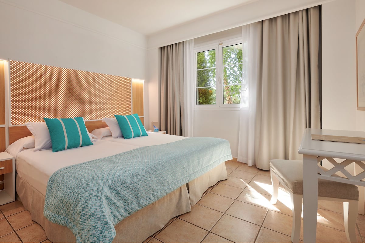 Una habitación de hotel con cama, escritorio y ventana con cortinas.