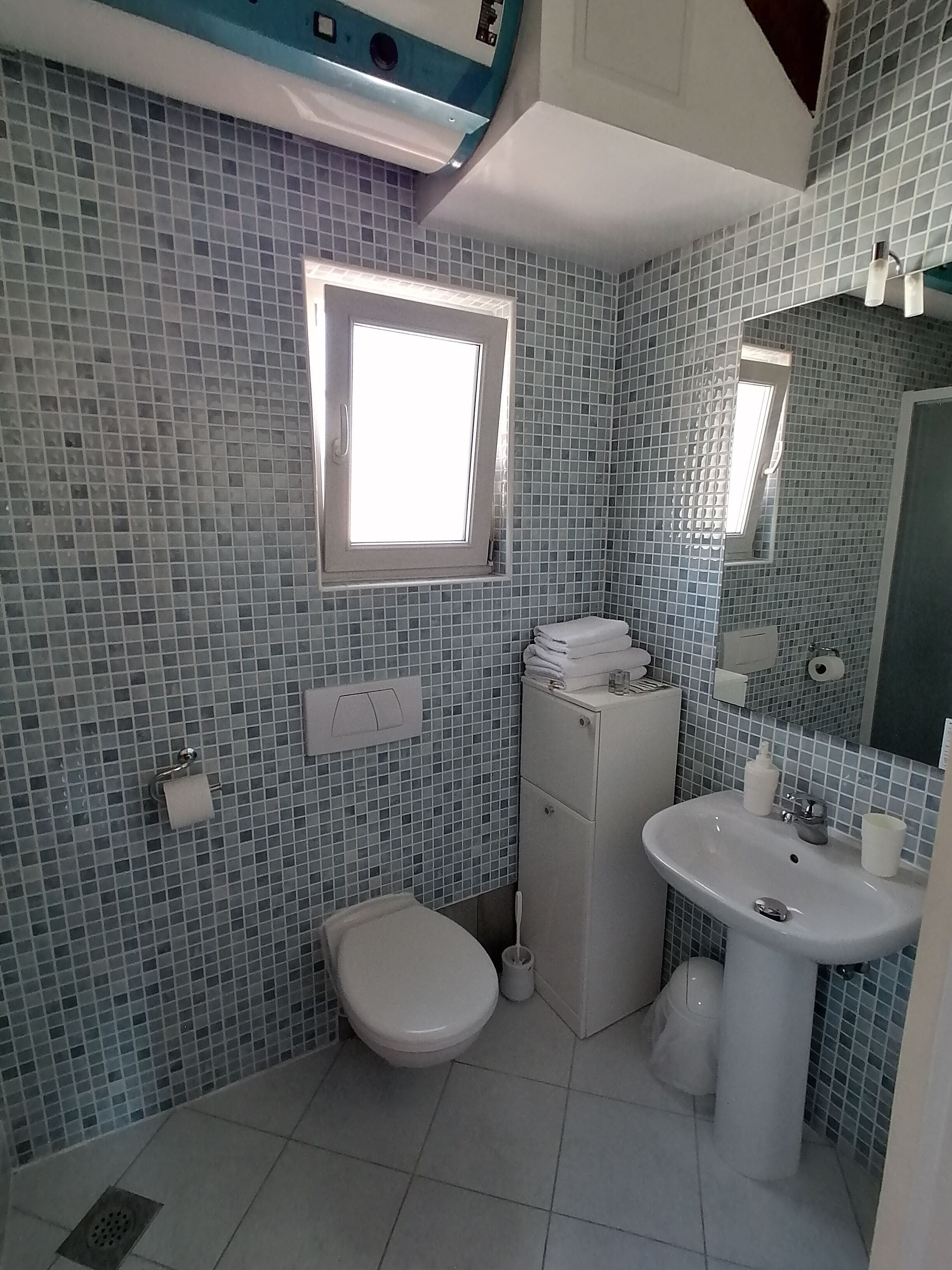 A bathroom with a toilet, sink, and a window.