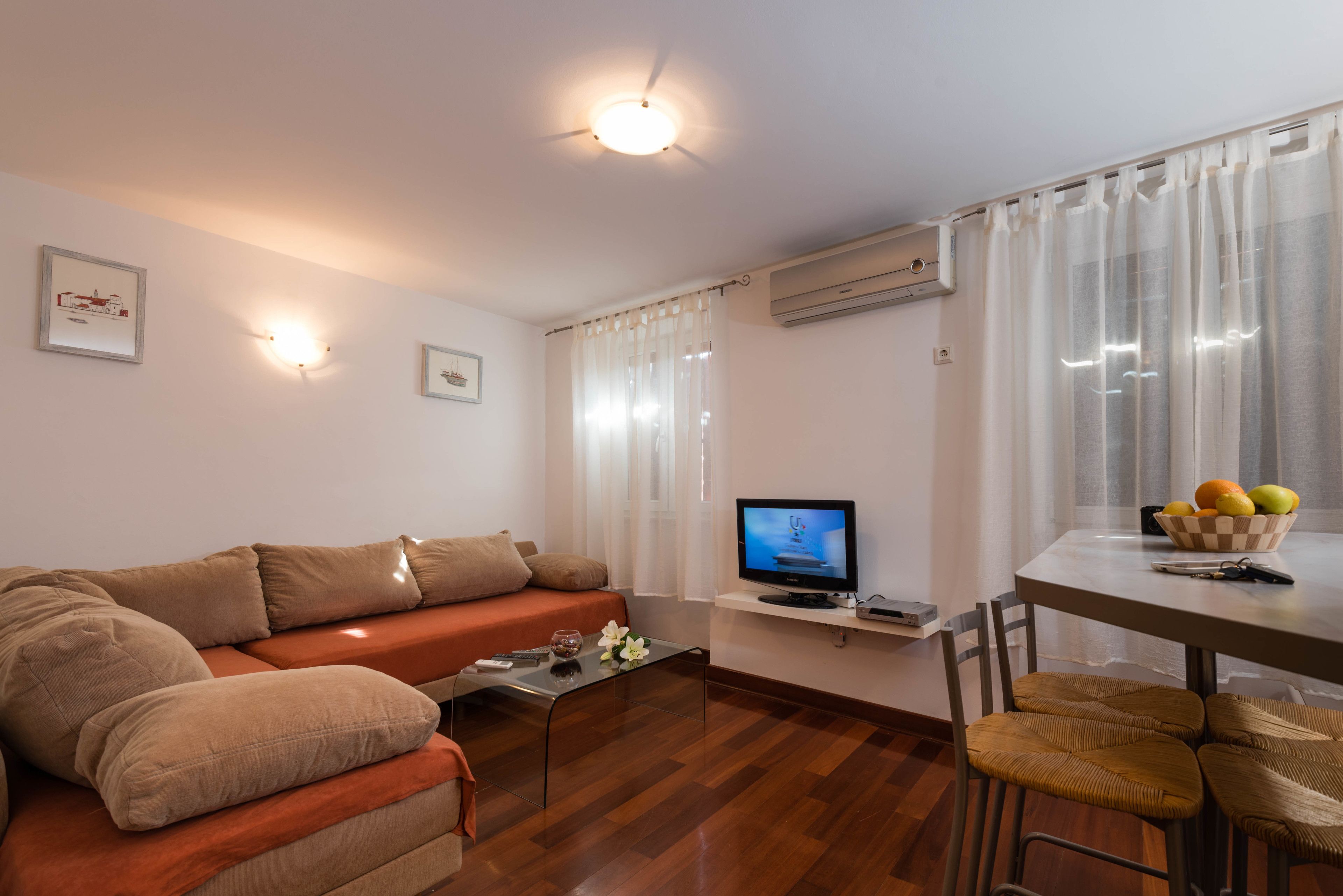Una sala de estar con un sofá, una mesa de centro, un televisor y un comedor con sillas y una mesa.