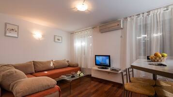 Una sala de estar con un sofá, una mesa de centro, un televisor y un comedor con sillas y una mesa.