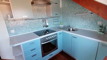 A kitchen with a blue tiled backsplash, a stainless steel sink, and a built-in oven.