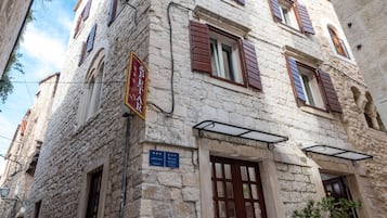 Traditional stone building with a classic facade, featuring evenly spaced windows and a wooden door.