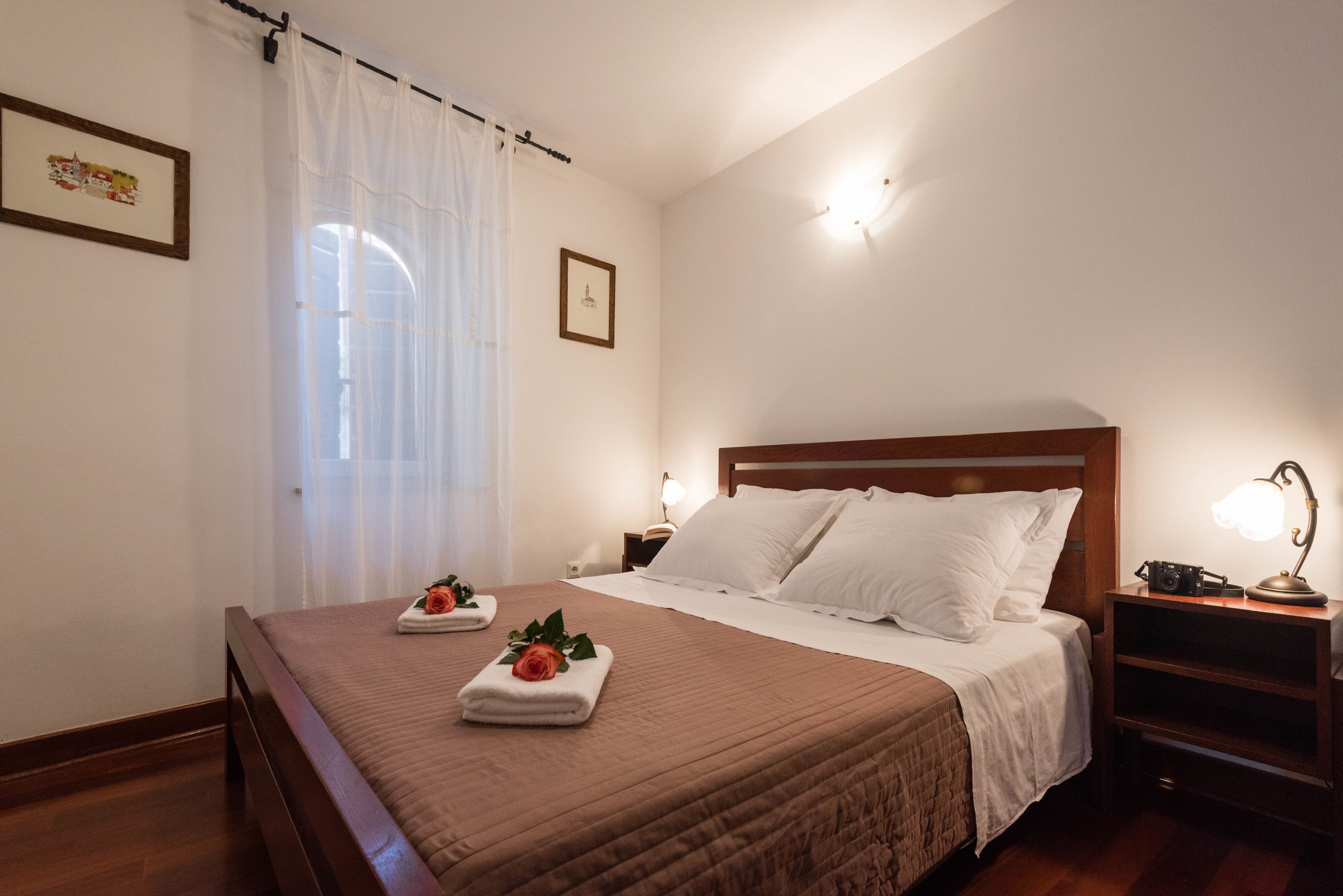 Una habitación de hotel con una cama, una mesita de noche, una lámpara y un cuadro en la pared.