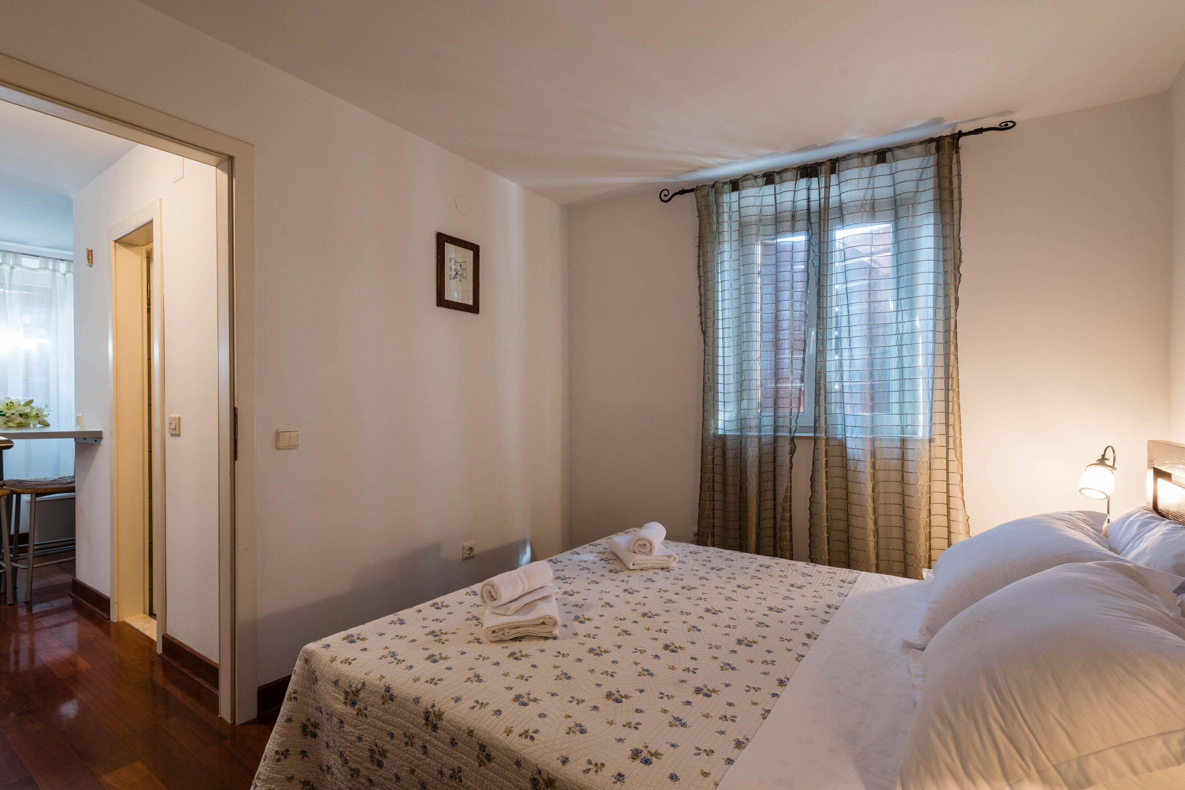 A hotel room with a bed, a desk, and a window with curtains.