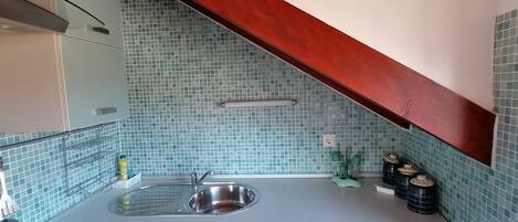 A kitchen with a sink, cabinets, and a tiled backsplash.