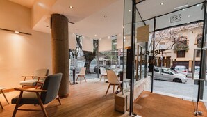A modern interior with wooden flooring, a large pillar, and seating areas with chairs. - Punta Trouville Hotel (Montevideo)