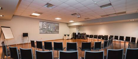 A conference room with rows of chairs, a projector screen, and a whiteboard.