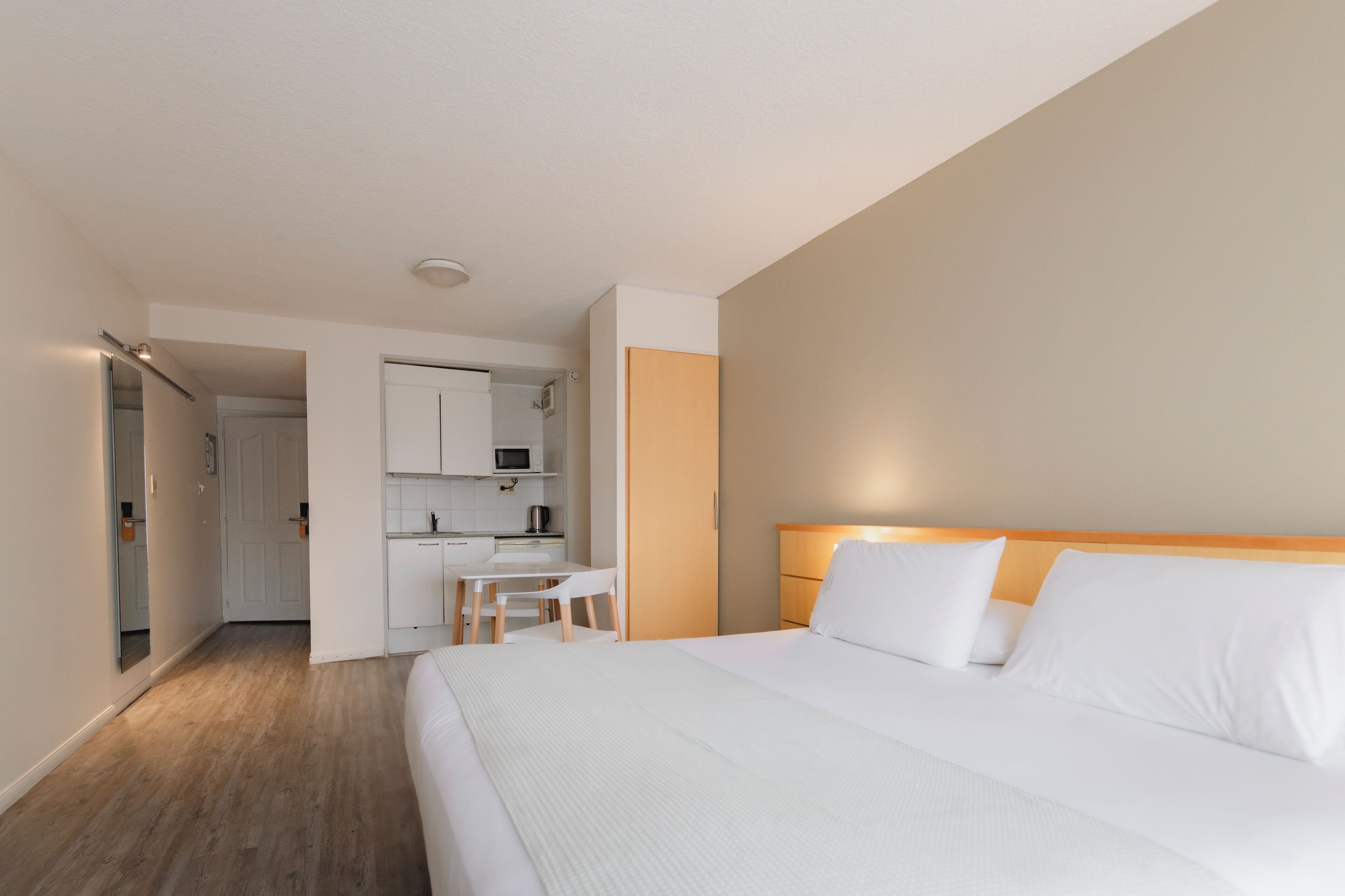 Een hotelkamer met een bed, een bureau en een kitchenette.