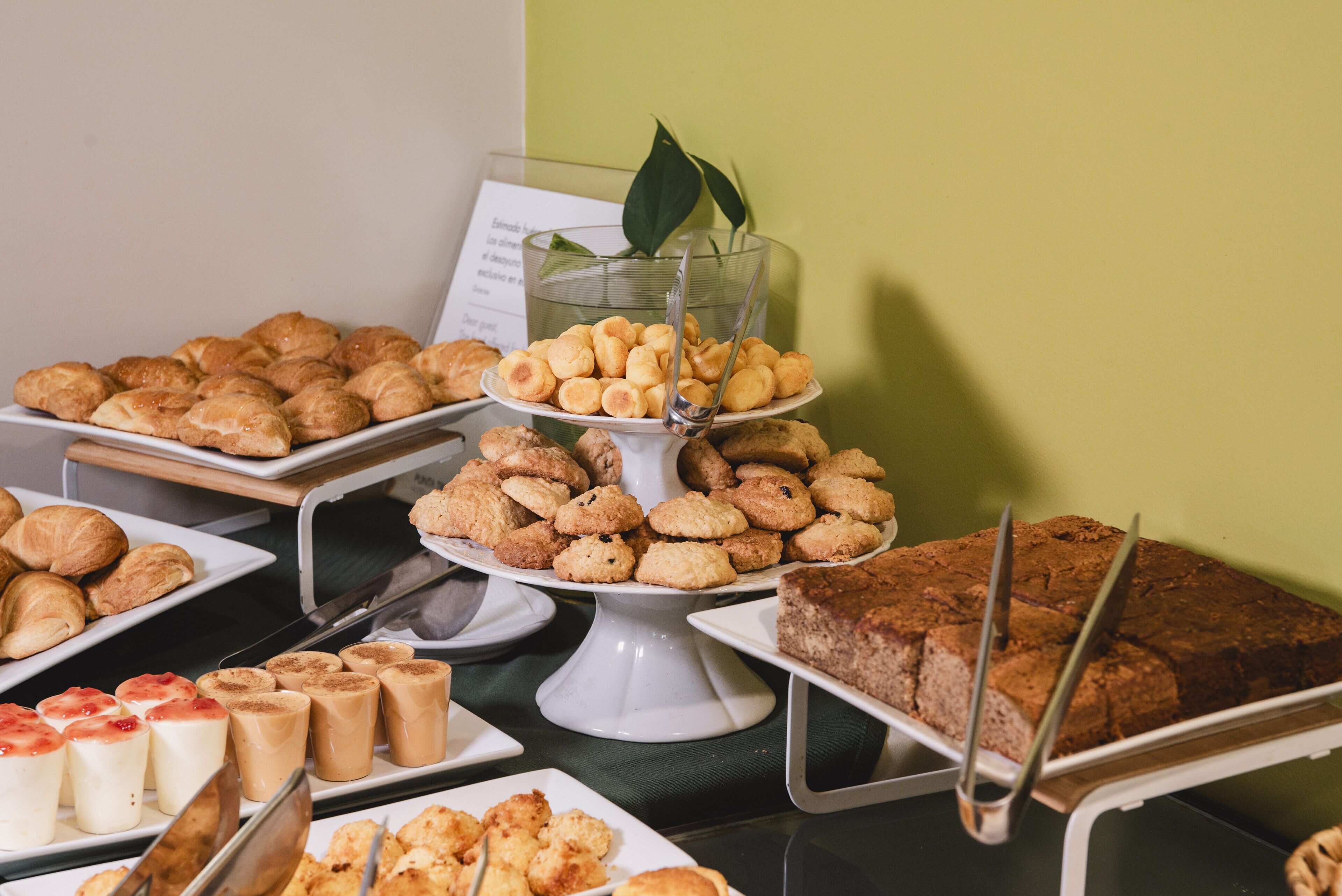 A buffet with various baked goods including pastries, cookies, and a cake.