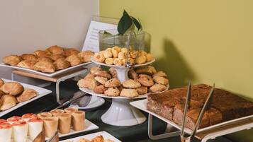 Un buffet proposant une variété de produits de boulangerie, notamment des viennoiseries, des biscuits et un gâteau.