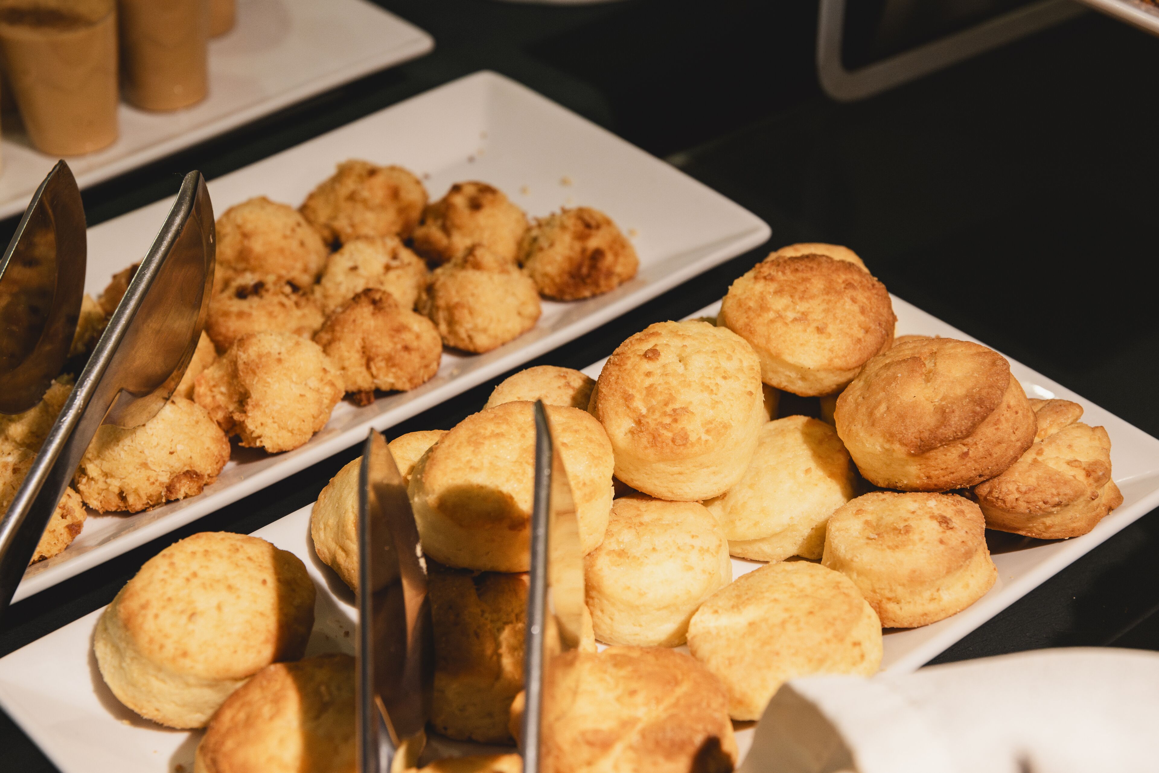 A buffet table with various baked goods, including biscuits and bread rolls.