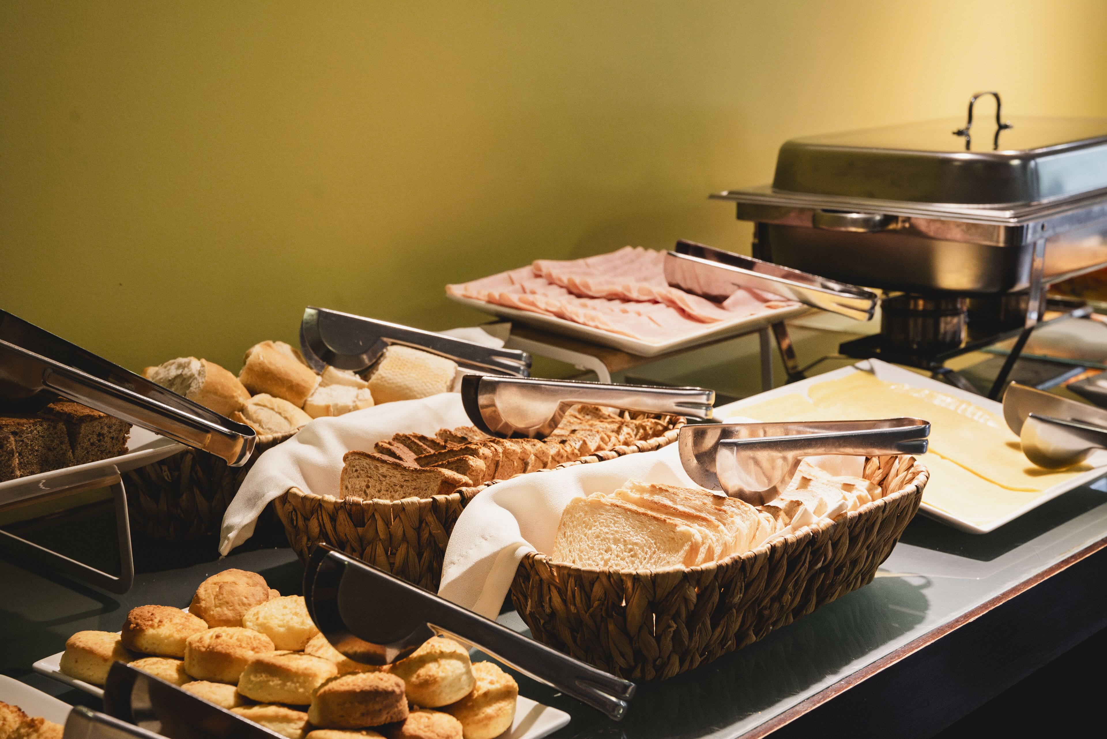 A buffet with various food items including bread, pastries, and meats.