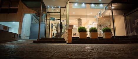 A modern building entrance with glass doors, a visible number 726, and potted plants.